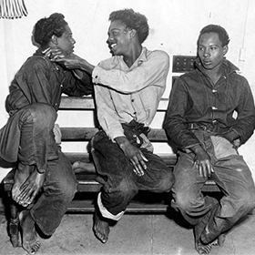 Three people sit together with mixed expressions.