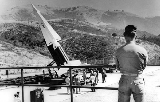 Soldier stands guard over poised Nike guided missile. Four Nike bases form main line of defense for critical Valley area. Sep. 8, 1960.
