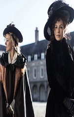 Two women in period dress stand in front of a large house. 