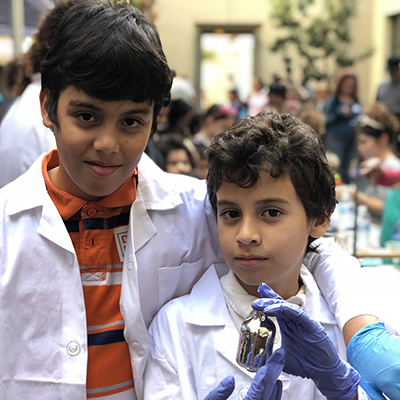 two boys in lab coats showing a beaker