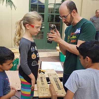 man demonstrating a power drill to a child