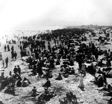 Bathers, picnickers, beach goers, and horse and carriages share a crowded beach in this early scene of Long Beach outings.