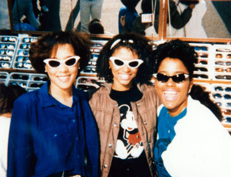 Three young women standing in front of a stand selling sunglasses, at Venice Beach, 1980 