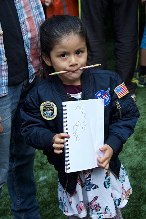 Child with pen in mouth, notepad in hand