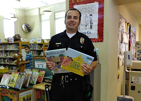 Officer Joseph Oseguera holding up two books