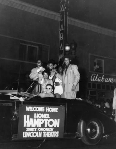 Lional Hampton rides in a Cadillac convertible with a group of people in front of Club Alabam on Central Avenue in Los Angeles.