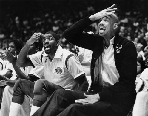 Lakers Magic Johnson and Kareem Abdul-Jabbar sitting on the sideline protesting a call made by officials.