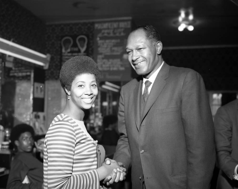 Tom Bradley is shown shaking hands with an unidentified woman