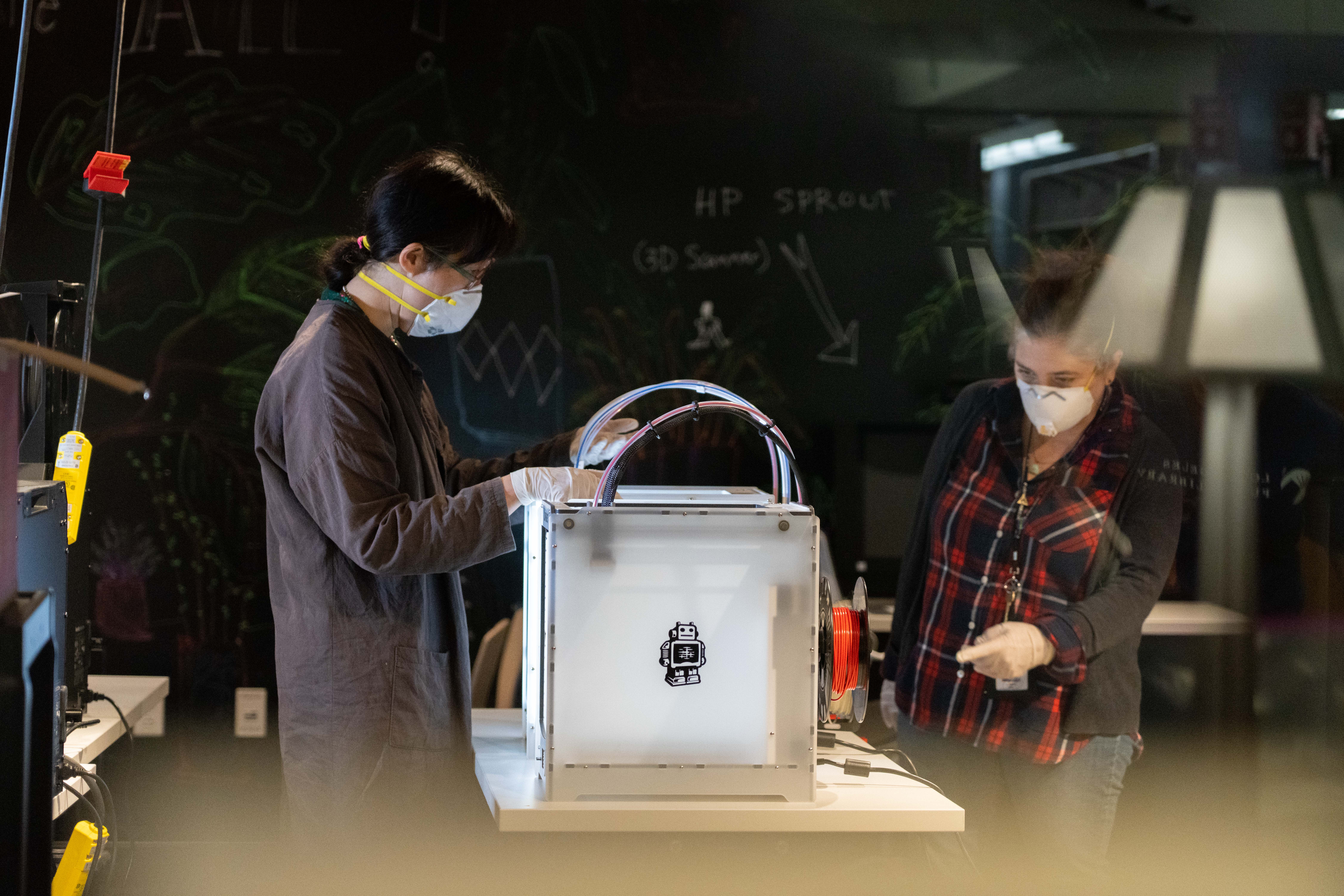 2 people usinga 3d printer create face shields