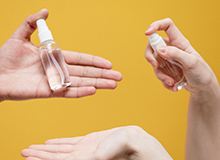 hands holding hand sanitizer bottles