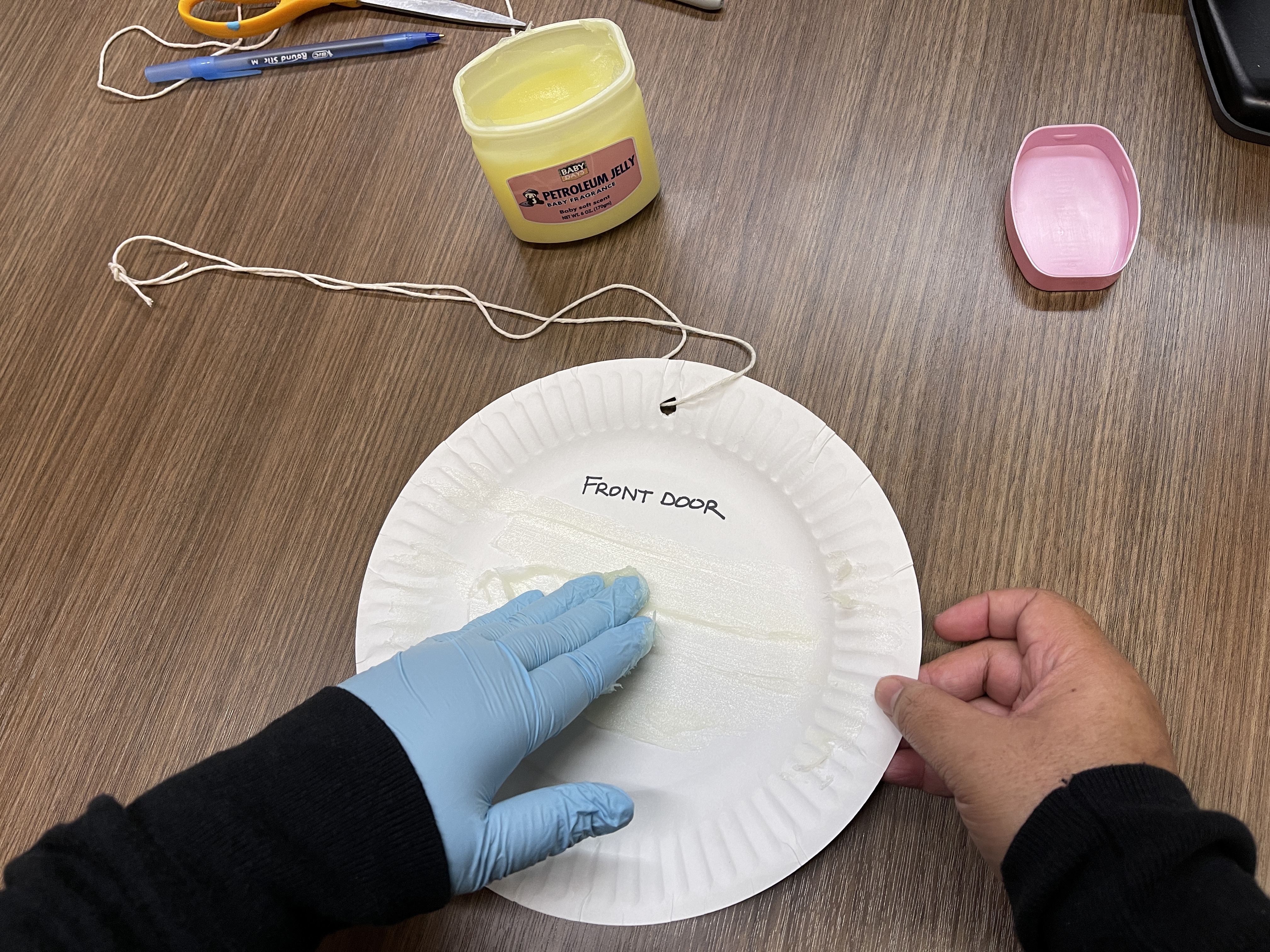 a person applying a thin coat of petroleum jelly on a paper plate