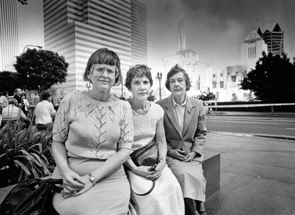 Three librarians sit across the street from Central Library during the Fire