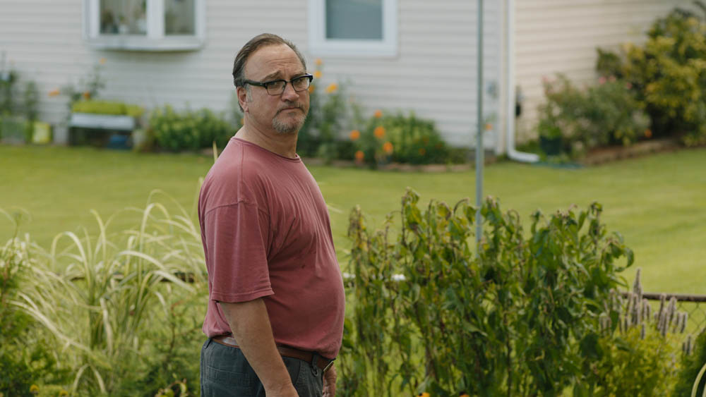 film still of Jim Belushi standing outside next to grass