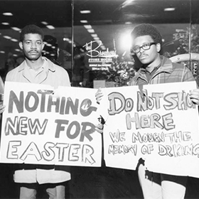 Two men hold signs protesting racism at the Broadway store.
