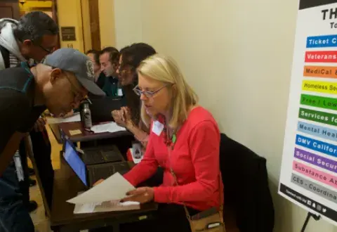 woman sitting at table displays paperwork for man