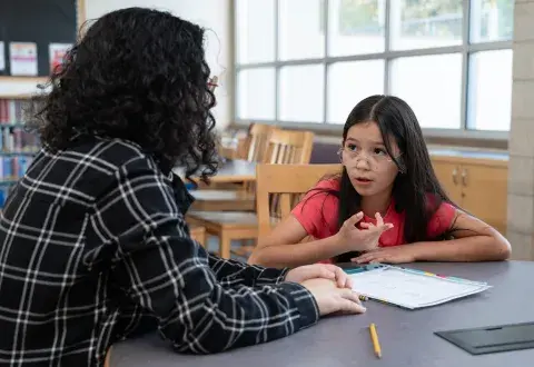 student talking to a tutor in a library