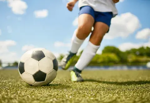 childs legs kicking a soccer ball