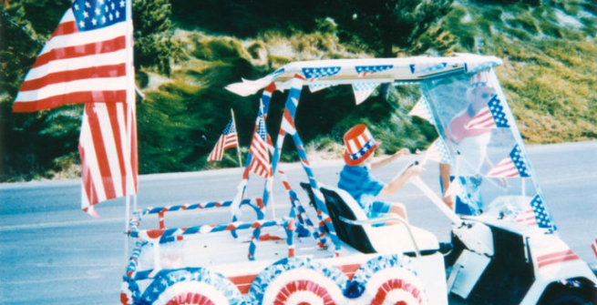 A boy drives a golf cart decorated for a Fourth of July parade in San Pedro.