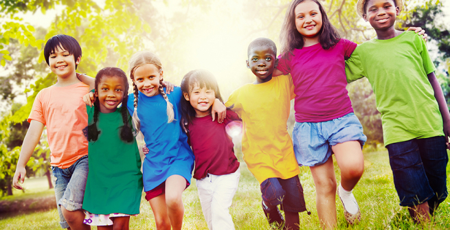 Smiling, diverse kids walking side by side in a grassy playground