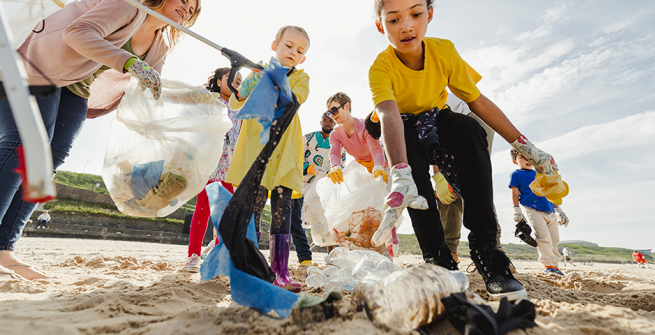 Kids and parents clean up trash from a beach