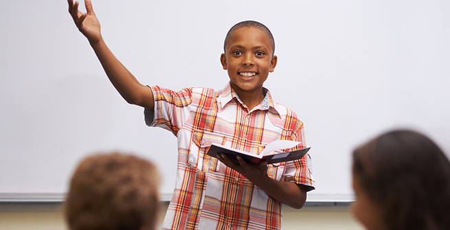 Young person speaking with enthusiasm in front of his classroom