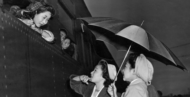 Young Japanese girls brave the early morning rain to bid farewell to friends leaving for Manzanar relocation camp