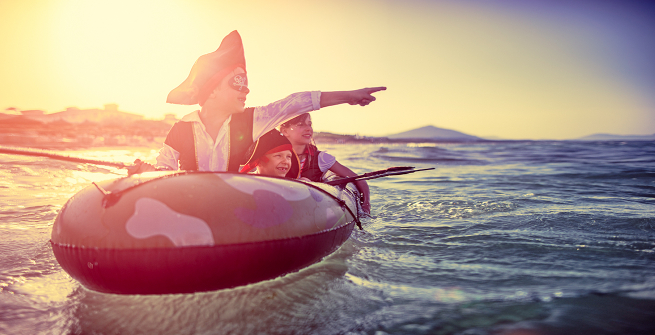 Kids dress in pirate clothes enjoying seafaring adventures while floating in a dinghy 