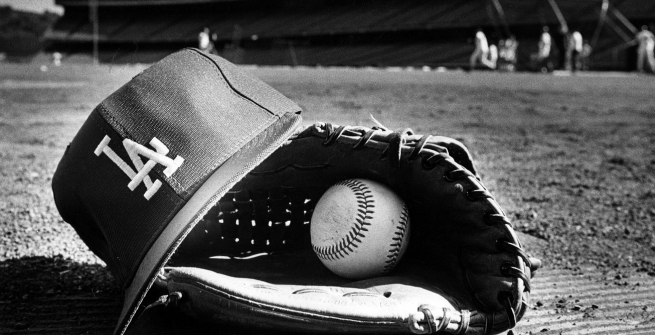 Close-up view of a Dodger player's hat, glove, and ball left on the field