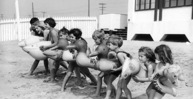 Children at the beach with floatie toys