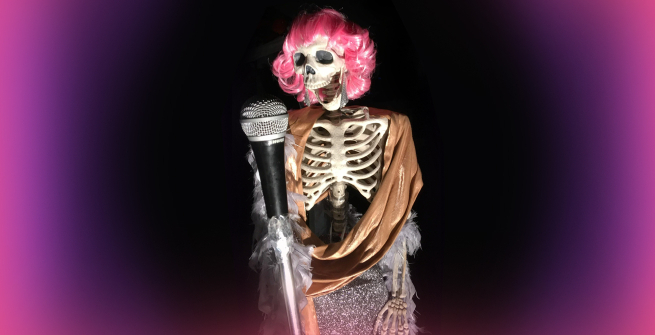 skeleton in a pink wig singing into a microphone