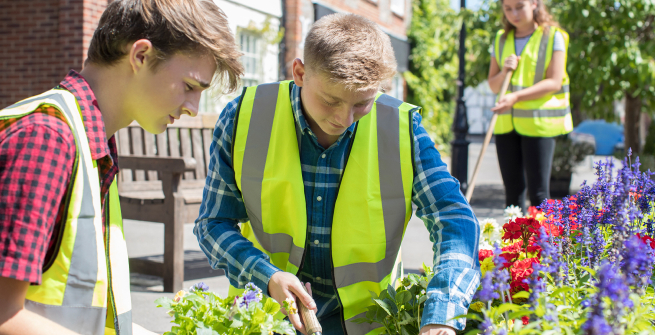 teens planting and cleaning wearing safety vests