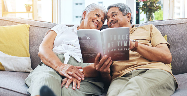 Happy, smiling senior couple on a sofa, reading a book together