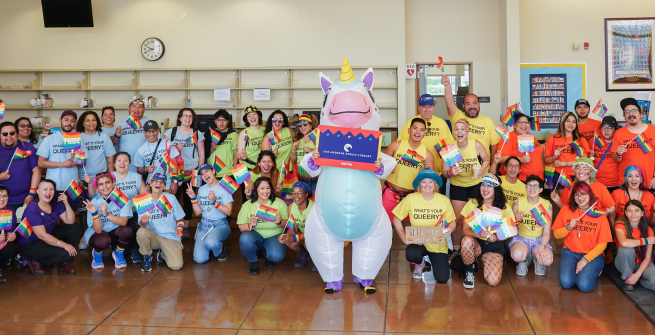 a person in a unicorn costume in front of a group wearing rainbow colored tshirts