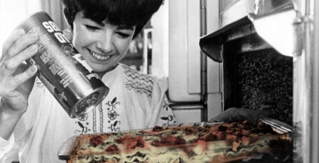 Women sprinkles cheese on lasagna