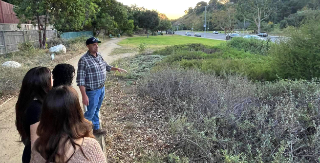 teens watching a gardner looking at native plants