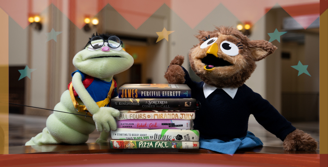 2 library puppets in the rotunda with a stack of books between them