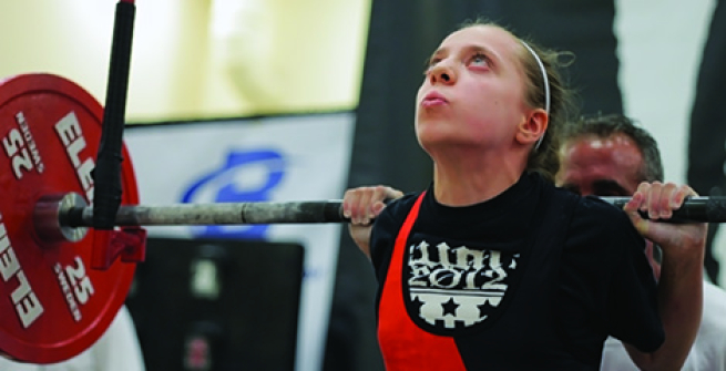 Young girl squatting a heavy barbell at a competition