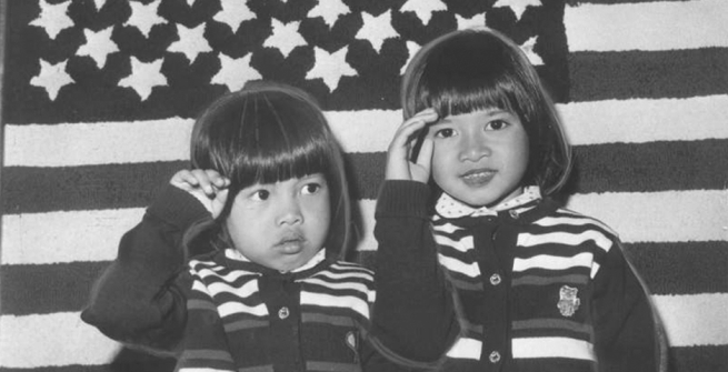 Two little girls, Pham Doan Phuong, 6, and Pham Quynh Phuong, 4, salute the American flag