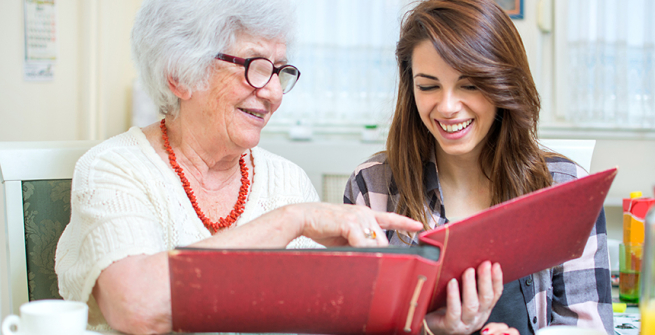 teen helping a senior look at a photo album