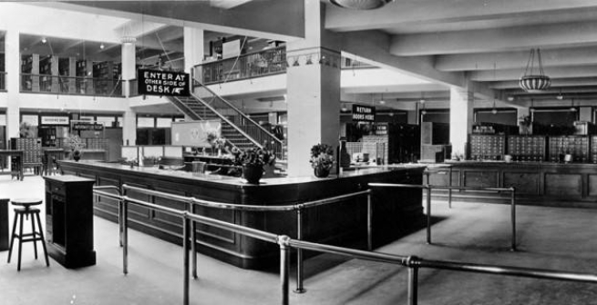 The eighth (aka main) floor of the library’s Metropolitan Building location (1914-1926) featured the Delivery Desk, where books were returned, and on the right in the background, the Registration Desk where borrowers picked up their library card. The photo was used in the May/June 1914 Monthly Bulletin of the Los Angeles Public Library, accessed via the Los Angeles Public Library California Index. Los Angeles Public Library Legacy Collection The eighth (aka main) floor of the library’s Metropolitan Building location 1914