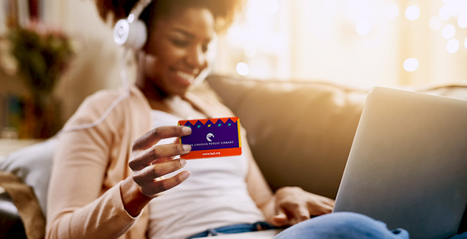 women holding her library card wearing headphones