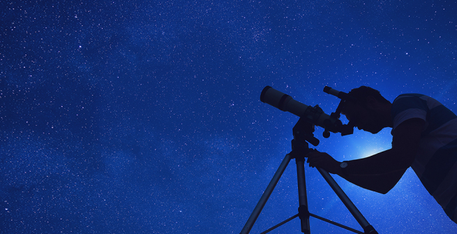 Looking up at the dark, starry night sky with a telescope  