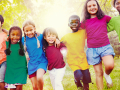 Smiling, diverse kids walking side by side in a grassy playground
