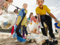 Kids and parents clean up trash from a beach