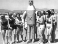 Robot on the beach surrounded by ladies in bathing suits