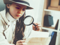 Young girl investigating photos with magnifying glass.