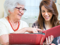 teen helping a senior look at a photo album
