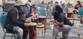 Music teacher working with child and mother playing drums in a group setting.