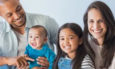 smiling family of four with parents, girl and baby boy