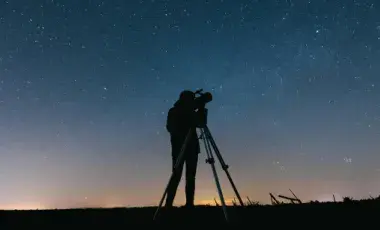 silhouette of a person and a telescope at dusk